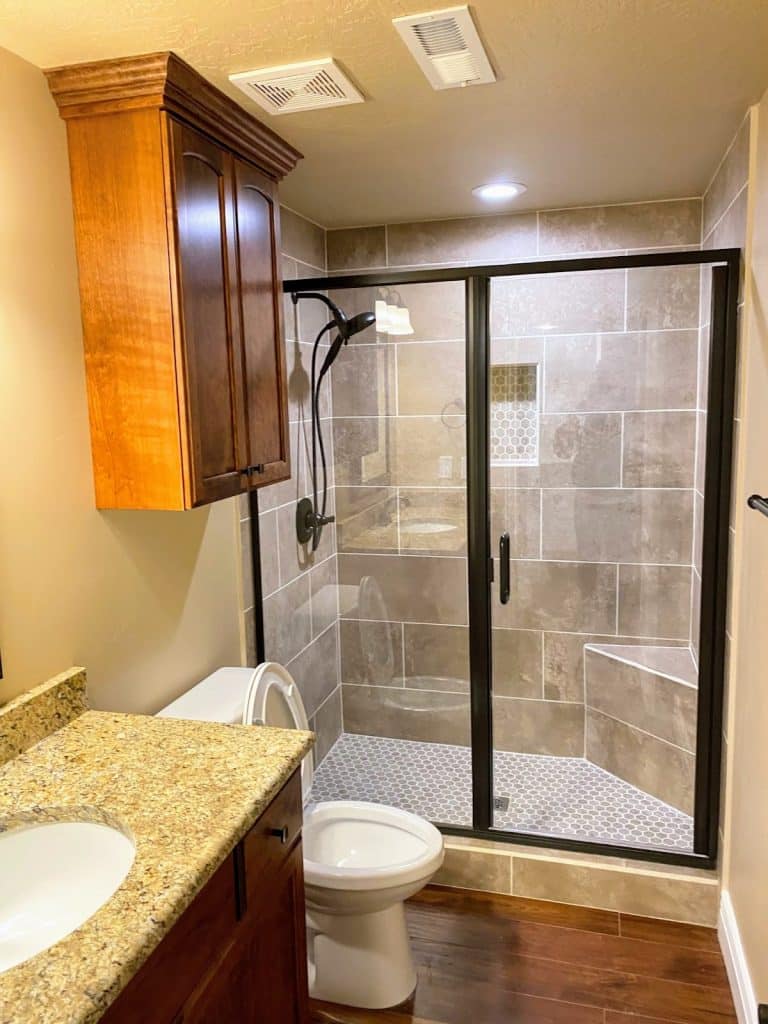 A remodeled basement bathroom featuring a shower and toilet. Get a basement remodel quote today.