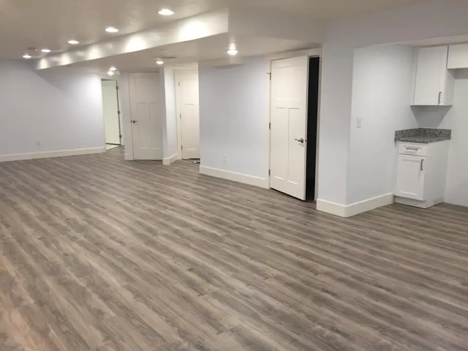 A renovated basement with wooden floors and white cabinets. Ideal for basement remodeling projects. - Creative Construction Solutions A renovated basement with wooden floors and white cabinets. Ideal for basement remodeling projects.