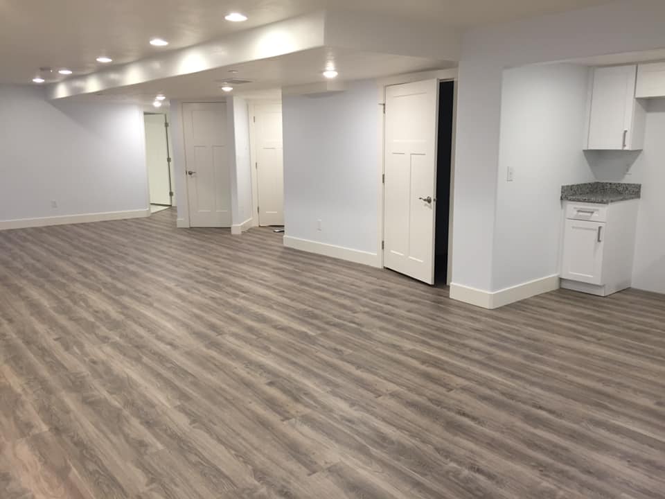 A renovated basement with wooden floors and white cabinets. Ideal for basement remodeling projects.