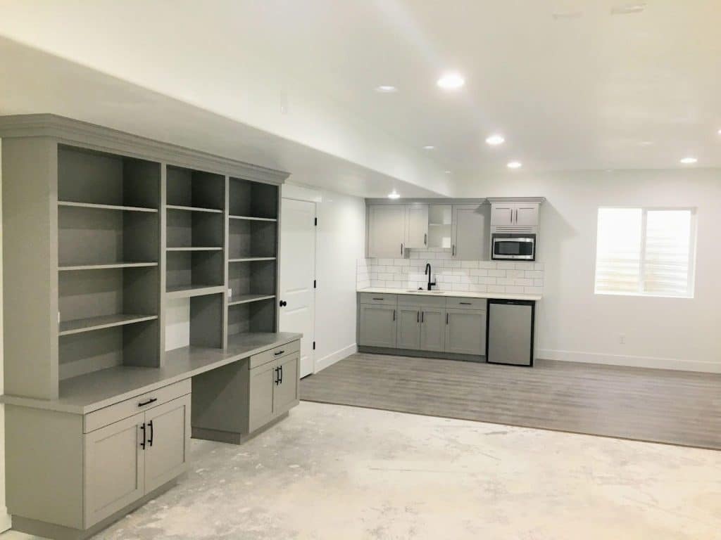 A tidy basement with a kitchen and well-arranged cabinets