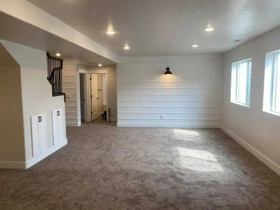 Basement room with plush carpet and clean white walls - Creative Construction Solutions Basement room with plush carpet and clean white walls