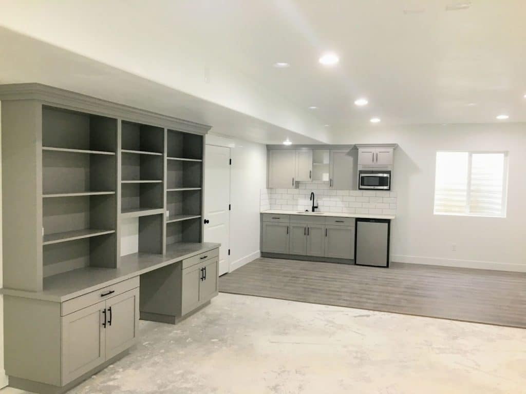 A clean, empty basement rental with gray cabinets and a desk.