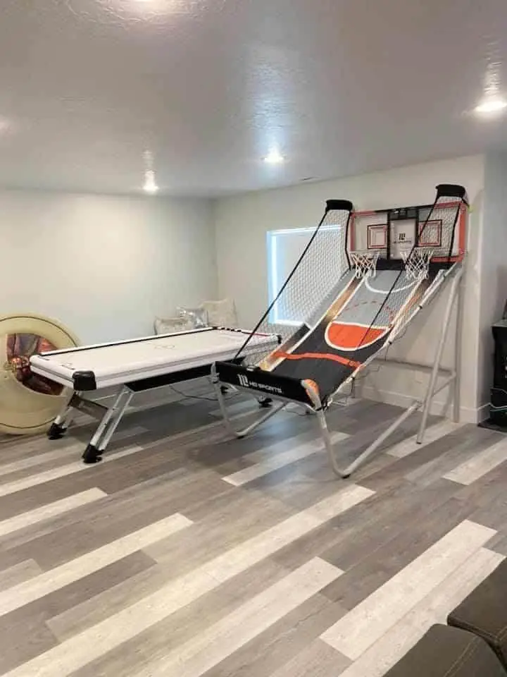 A stylish basement game room featuring a pool table, basketball hoop, and a cozy couch for movie lovers to enjoy. - Creative Construction Solutions A stylish basement game room featuring a pool table, basketball hoop, and a cozy couch for movie lovers to enjoy.