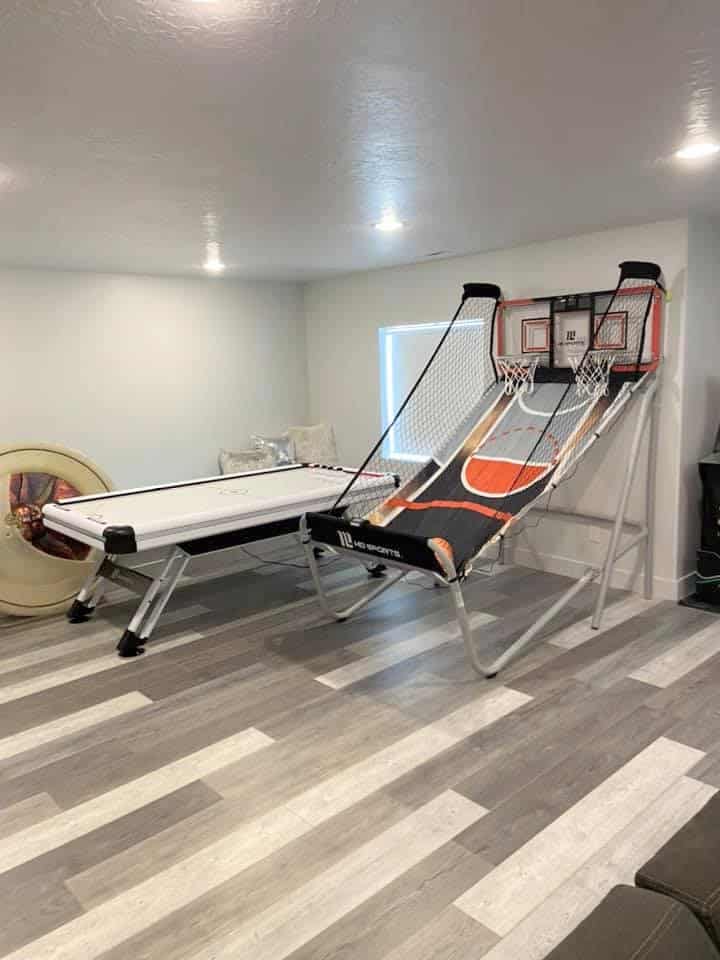 A stylish basement game room featuring a pool table, basketball hoop, and a cozy couch for movie lovers to enjoy.