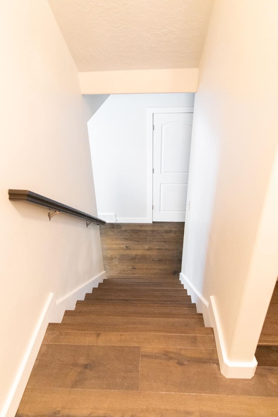 A view of basement stairs featuring wooden floors and white walls, showcasing the renovation process in progress.