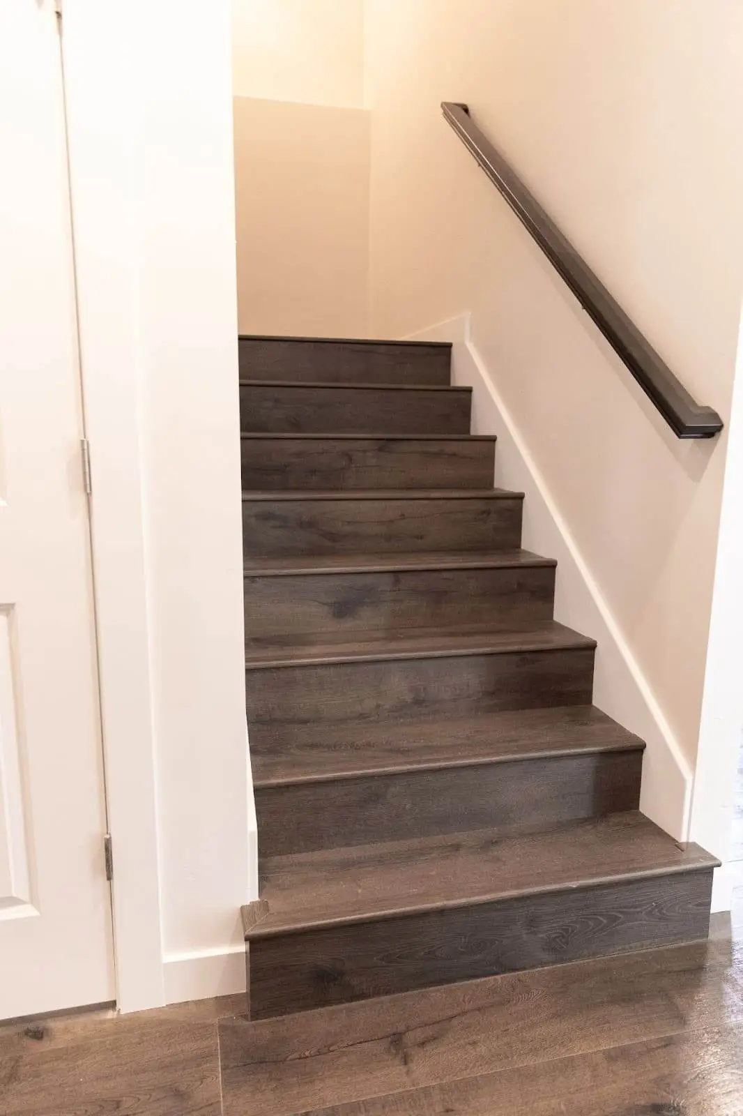 A wooden staircase leading to a basement, featuring a sleek black railing, showcasing the renovation process. - Creative Construction Solutions A wooden staircase leading to a basement, featuring a sleek black railing, showcasing the renovation process.