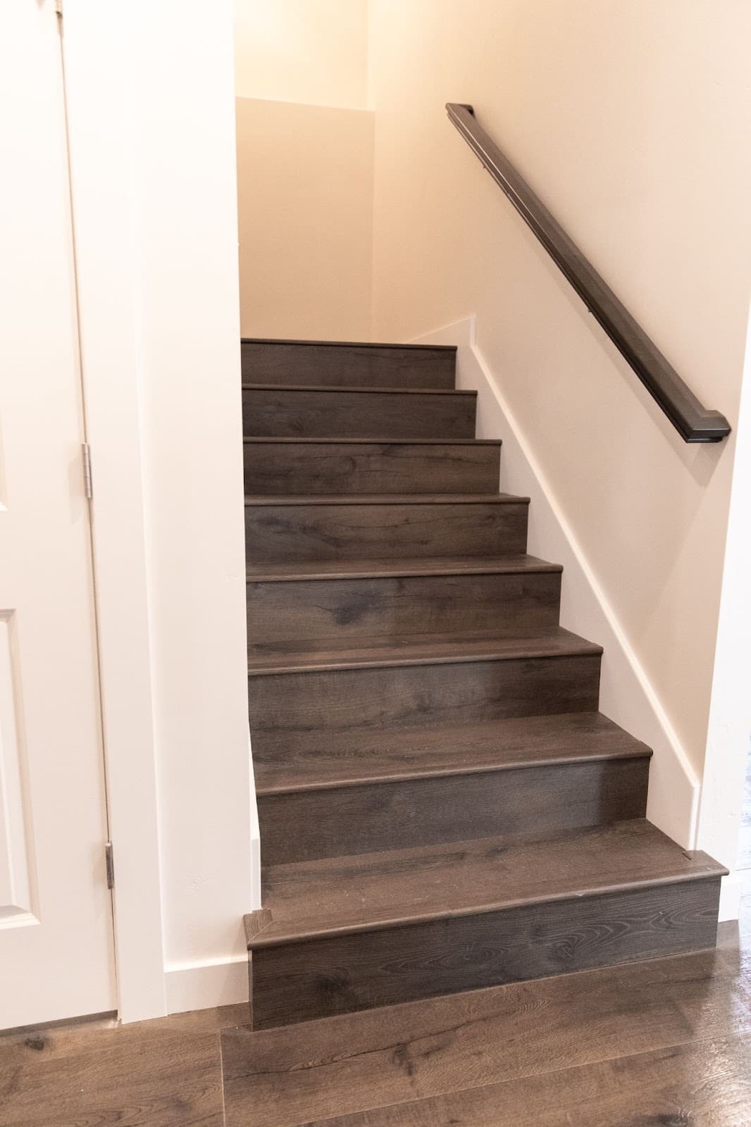 A wooden staircase leading to a basement, featuring a sleek black railing, showcasing the renovation process.