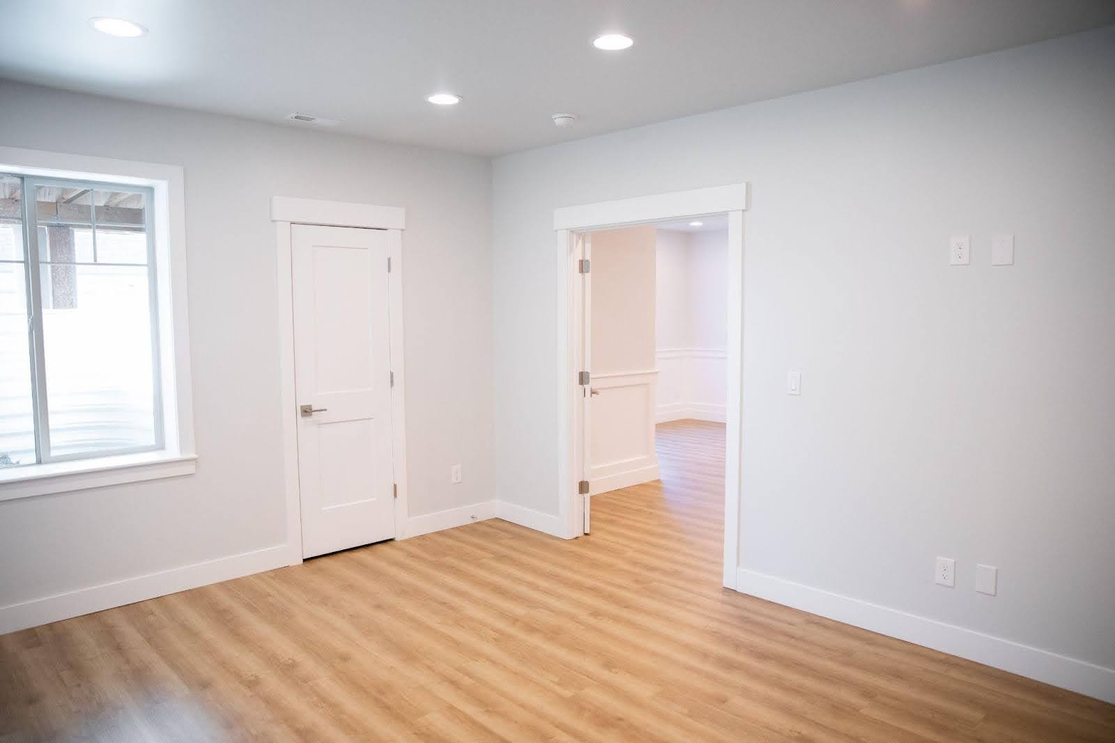 A vacant room with polished hardwood floors and white doors, emphasizing simplicity