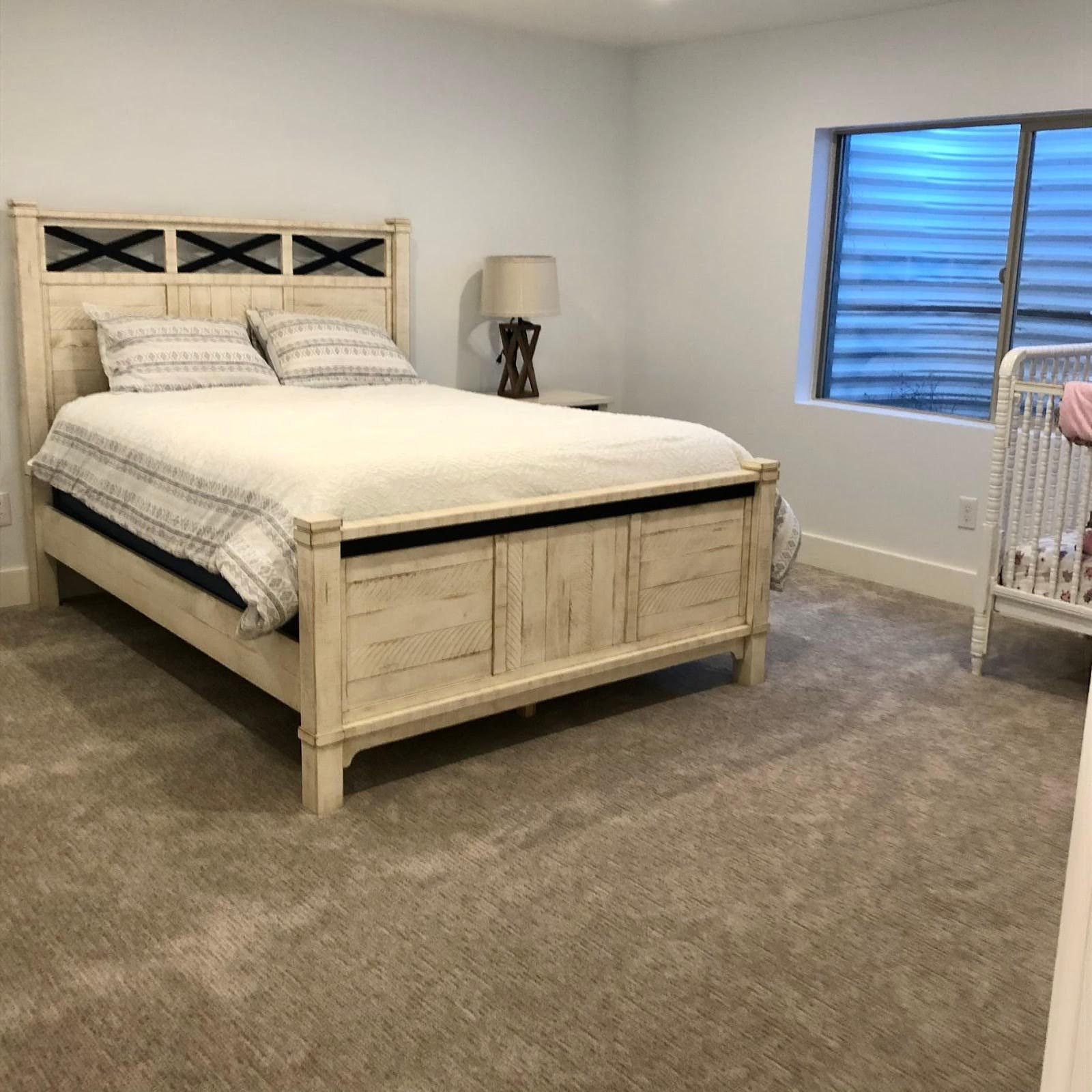 A serene bedroom with a bed, dresser, and crib, designed for comfort