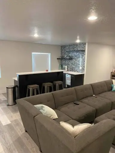 Modern basement man cave with a cozy sectional sofa, bar area, and sleek finishes.