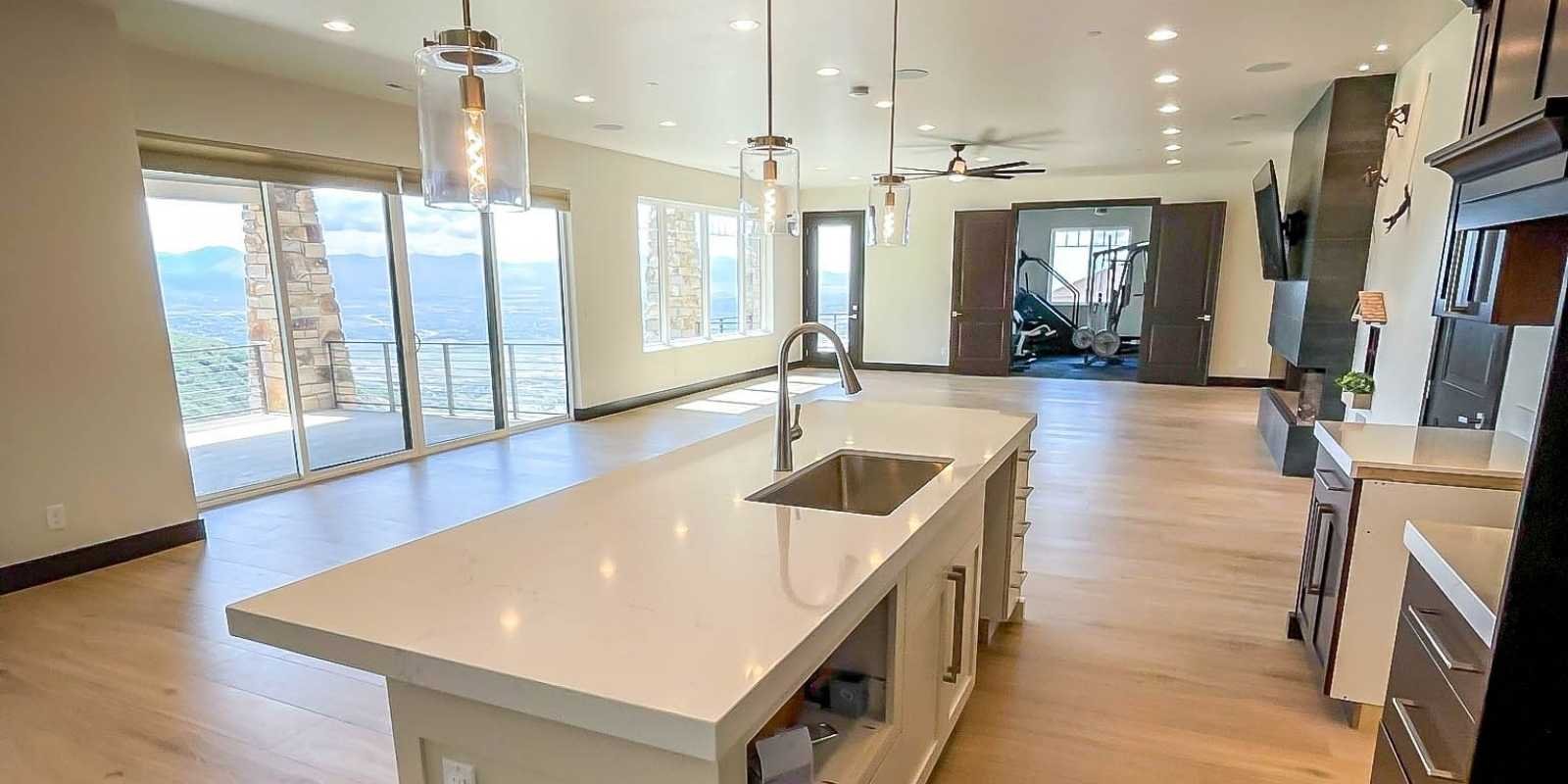 basement finishing building codes saratoga springs, utah: what homeowners need to know 2 A cream-themed open concept basement with warm wood floors and a prominent kitchen island in the foreground, highlighting a successfully completed project following a basement finishing permits Saratoga Springs code compliance guide.