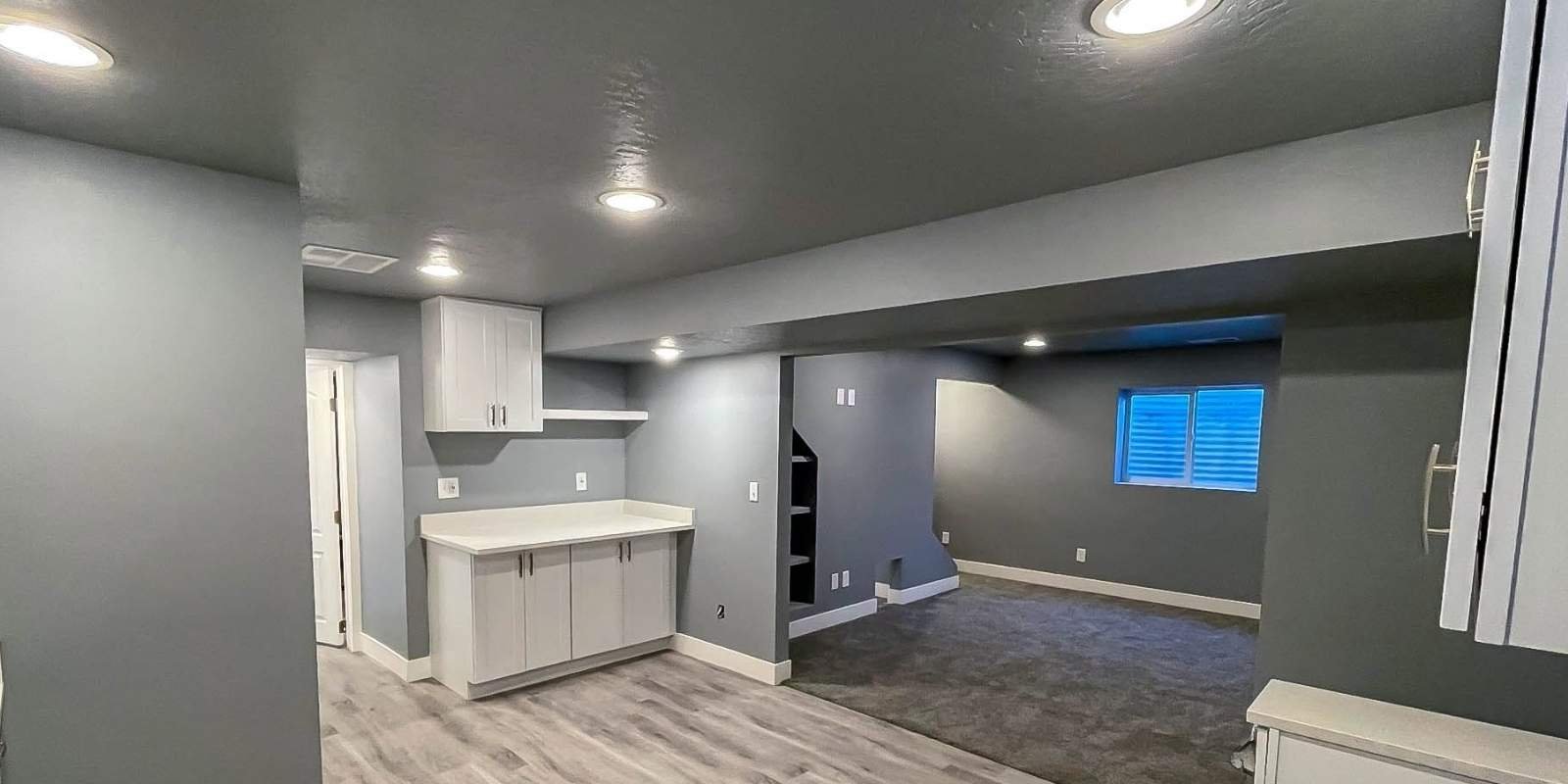 A sleek, gray finished basement featuring modern lighting and clean lines, illustrating the type of completed project that requires a Basement remodeling permits Bluffdale Utah application form.