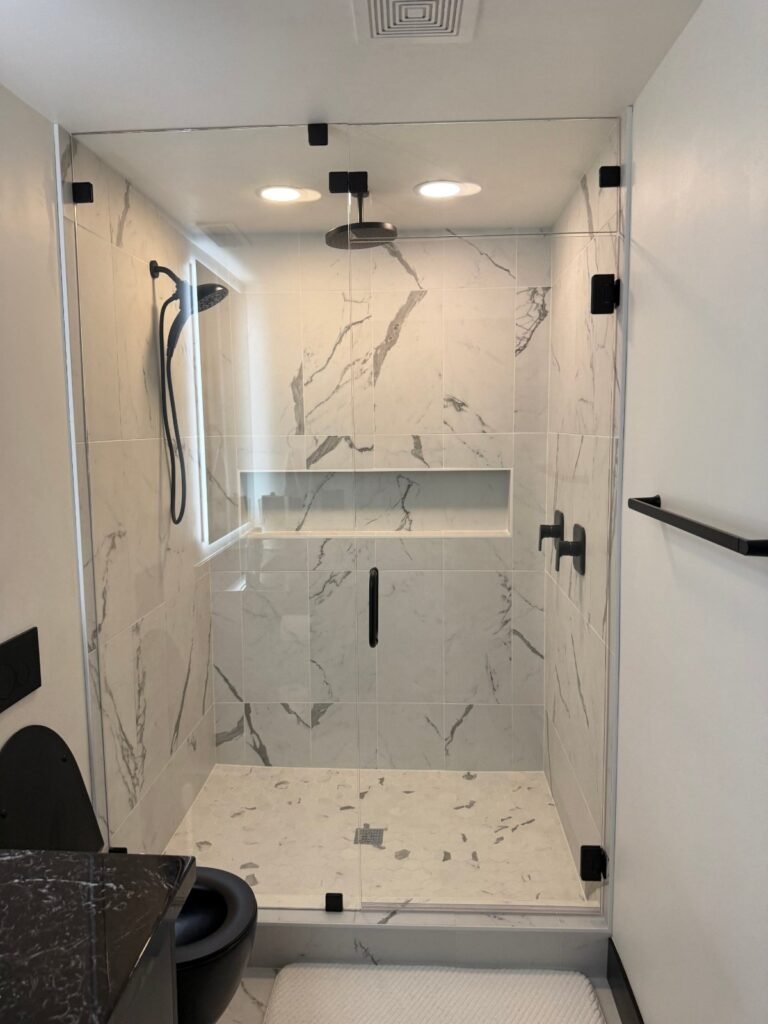 Custom marble tile shower with black fixtures and built-in niche
